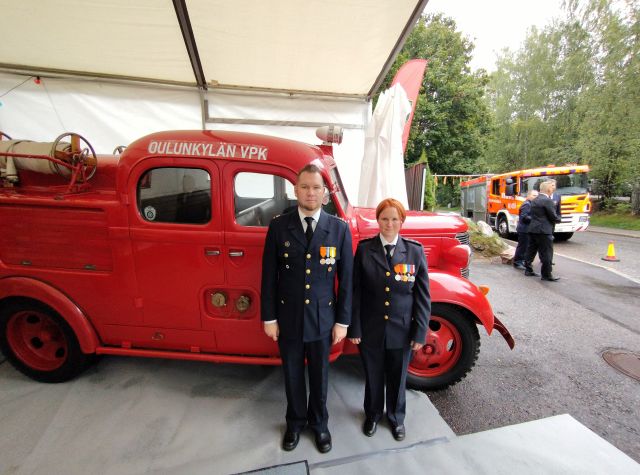 Mies ja nainen univormuissa paloauton edessä