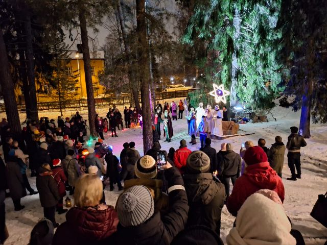 Ihmisiä kokoontuneena pihalle katsomaan esitystä talvisessa säässä