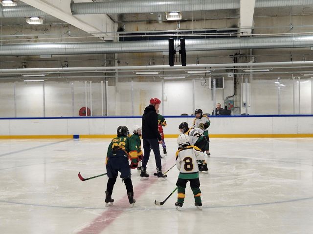 lapsia pelaamassa jääkiekkoa jäähallissa