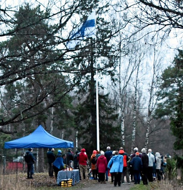 Ihmisiä kokoontuneena talviseen puistoon nostamaan lippua salkoon