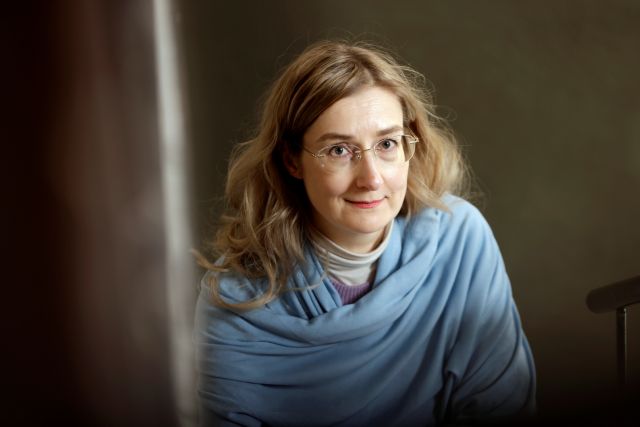 Kirjailija Emmi Itäranta kuvattuna sisätiloissa tummahkoa taustaa vasten