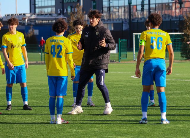 valmentaja ja jalkapalloa pelaavia nuoria kentällä