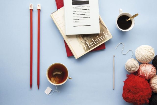 flat lay kuvassa neulepuikot, muistikirja, kahvikuppi lankakeriä ja kirja